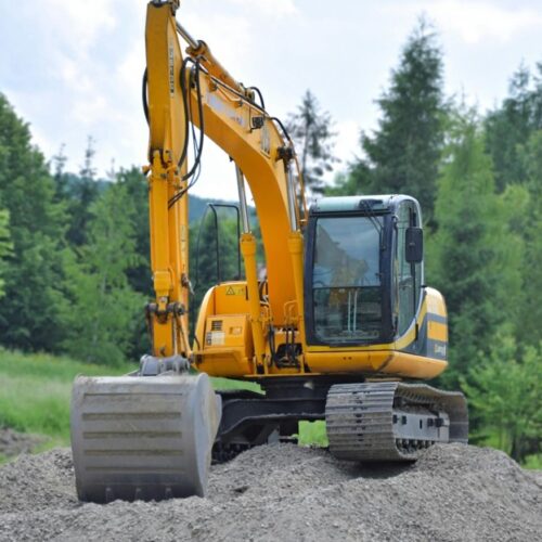 Excavator digging rock in forested mining area, highlighting commitment to safety and training