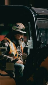 Older mine worker seated in heavy machinery wearing full protective equipment, highlighting tailored safety training