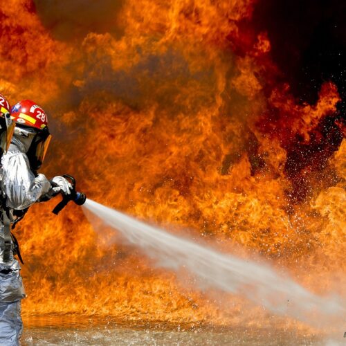 Firefighter extinguishing fire illustrating the role of flame-resistant equipment and trailing cables in mine safety.